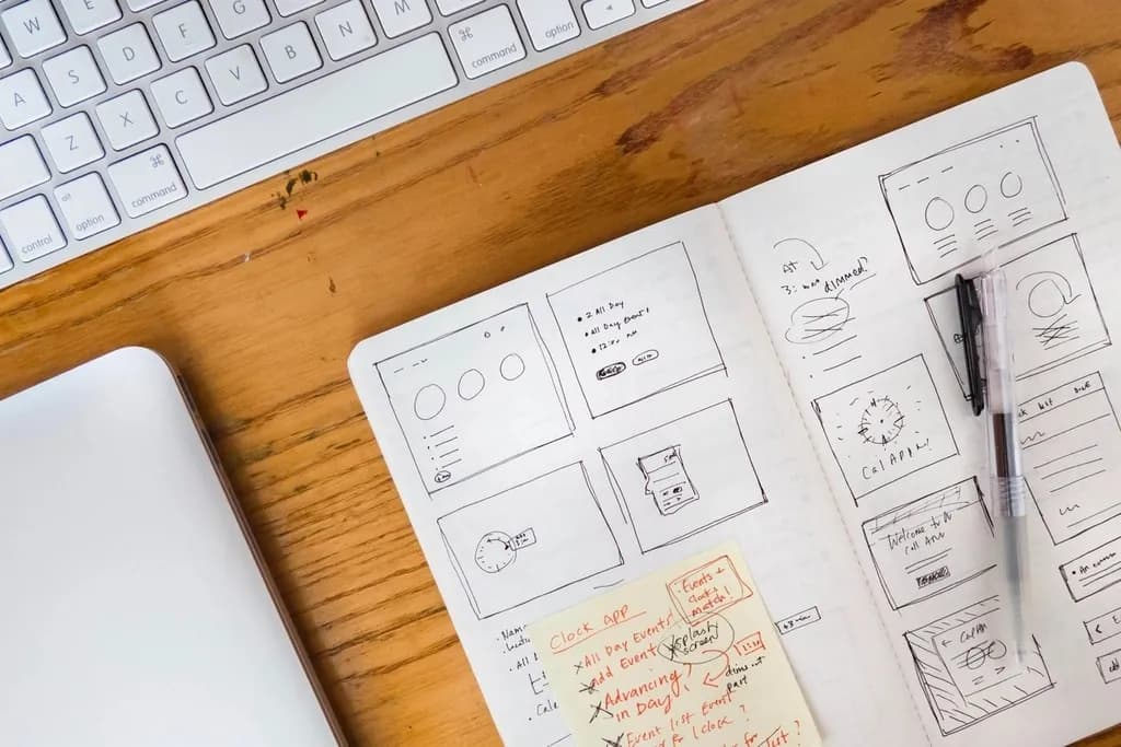 Bocetos de diseño de una página web en una libreta junto a un teclado